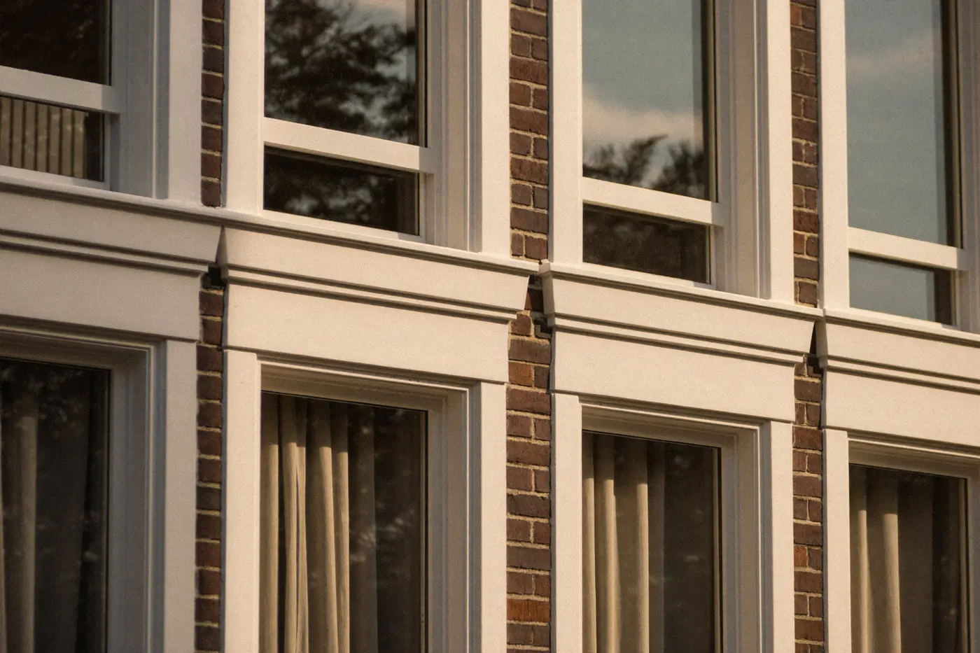 Strak geschilderde witte houten kozijnen in een bakstenen gevel
